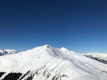 Scenic view of snowcapped mountains against clear blue sky