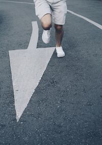 Low section of man running by arrow road sign 