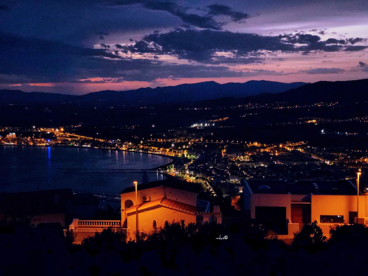 architecture, built structure, building exterior, sky, city, cloud - sky, illuminated, night, water, high angle view, cityscape, nature, mountain, building, residential district, outdoors, no people, dusk, city life, bay