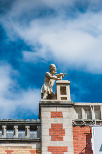 Low angle view of statue against building against sky