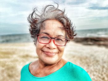 Close-up portrait of smiling senior woman wearing eyeglasses at beach