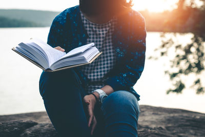 Man holding book while sitting on beach