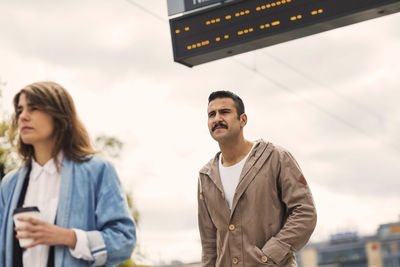 Low angle view of male and female passengers walking at tram station