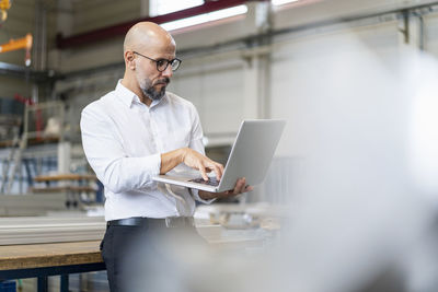 Businessman using laptop in factory