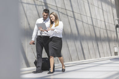 Businessman and businesswoman with digital tablet on the move