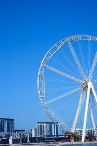 Low angle view of ferris wheel against clear blue sky