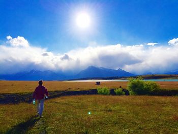 Rear view of man walking on grassy field