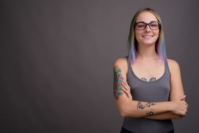 Portrait of smiling young woman standing against wall