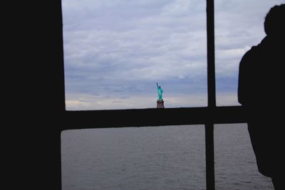 Silhouette man standing by sea against sky during sunset