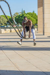 Man exercising with battle rope in park