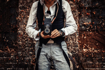 Unrecognizable photographer using vintage medium format photo camera while photographing outdoors.