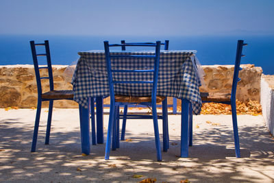 Empty chairs on beach against sky