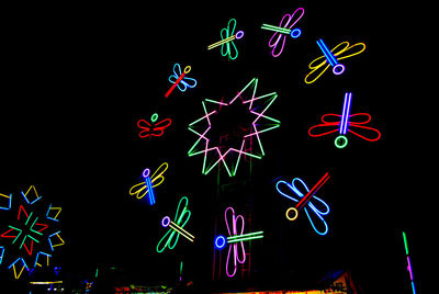 Low angle view of illuminated lighting equipment against black background