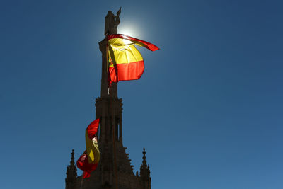 Low angle view of flag statue against clear blue sky