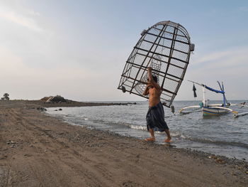 Boy standing on beach against sky