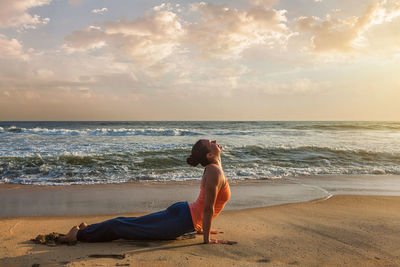 Full length of woman on beach against sky during sunset