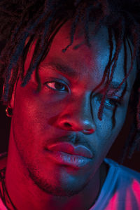 Portraits of beautiful african young man under blu and red lights