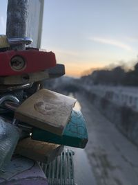Close-up of padlocks on railing against sky during sunset