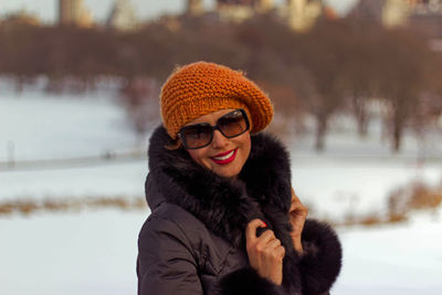 Smiling woman wearing warm clothing and sunglasses during winter