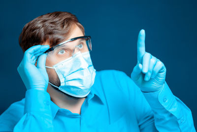 Doctor wearing mask gesturing against blue background