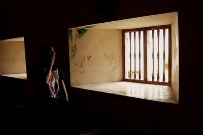 Woman standing by window at old house