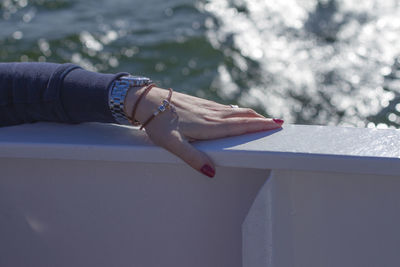 Cropped hand of woman holding railing against sea