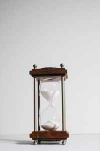 Close-up of clock on table against white background