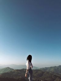 Woman standing on mountain against clear sky