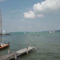 Sailboats moored in sea against sky