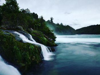 Scenic view of waterfall by sea against sky