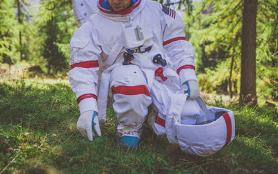 Low section of curious astronaut crouching in forest