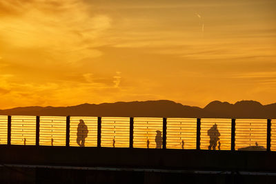 Scenic view of harbor with silhouette people during sunset