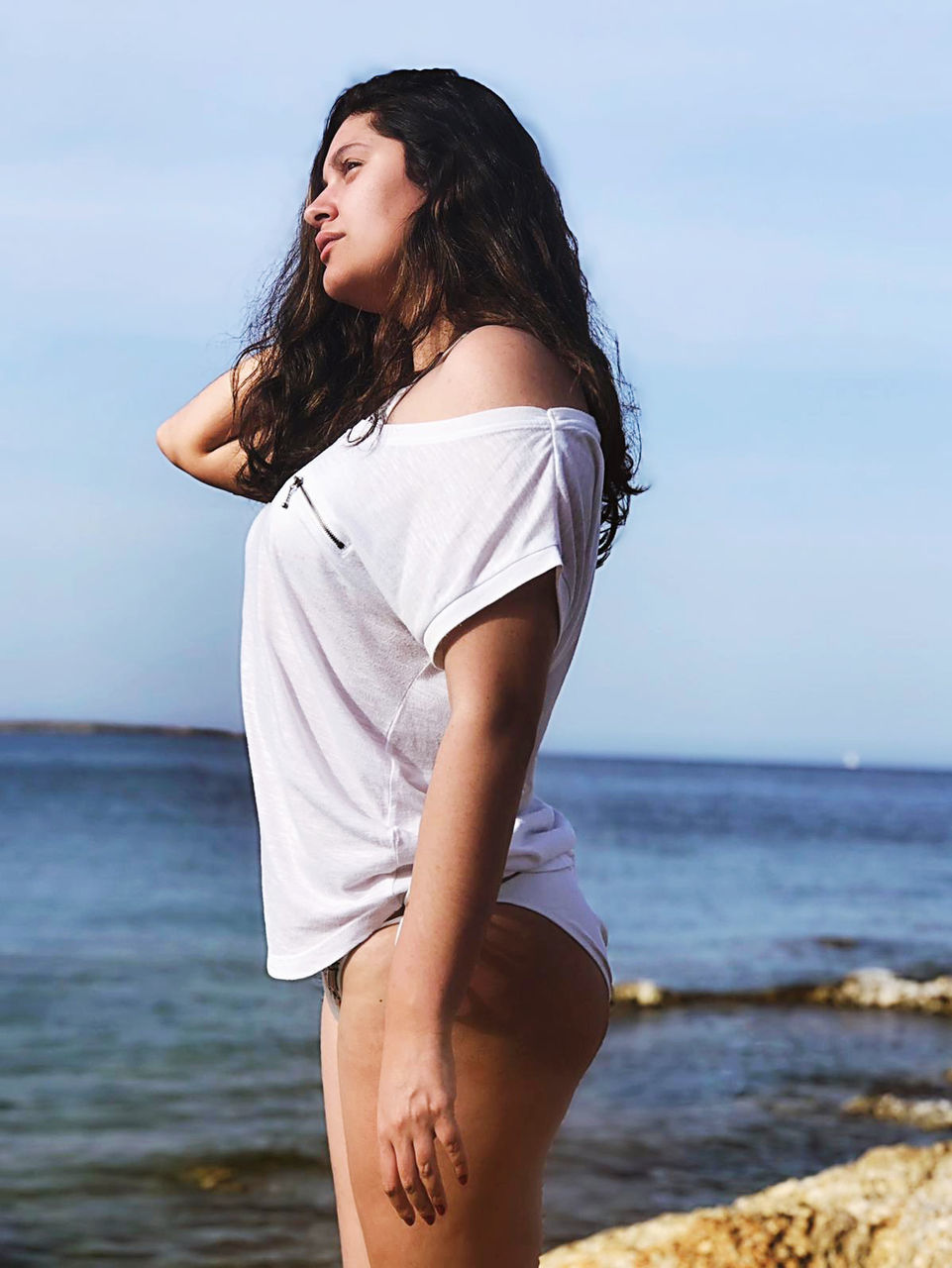 one person, sea, water, leisure activity, young adult, long hair, lifestyles, real people, beach, casual clothing, sky, hairstyle, young women, hair, horizon over water, three quarter length, horizon, standing, beauty, beautiful woman, outdoors