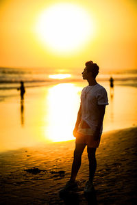 Full length of man standing on beach during sunset