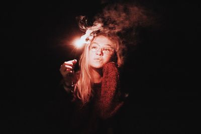 Portrait of young woman against black background