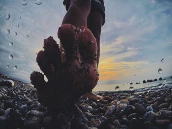 Person on rocks at beach against sky