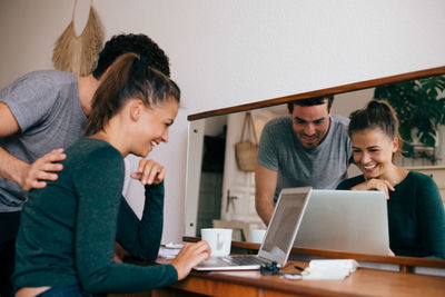 Boyfriend and girlfriend smiling while looking at laptop in bedroom