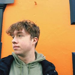 Portrait of boy looking away against yellow wall