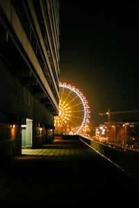 Illuminated buildings and ferris wheel at night