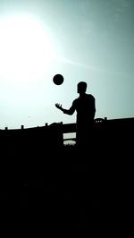 Silhouette man playing against clear sky