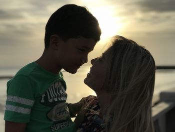 Side view of mother and son standing against sky