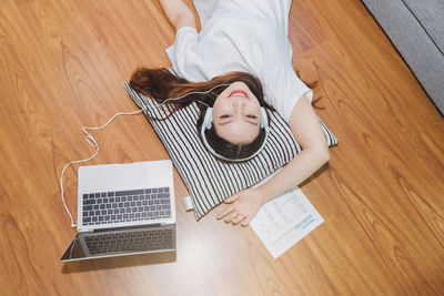 High angle view of girl using laptop on hardwood floor