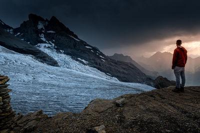 Man standing on mountain against sky during winter