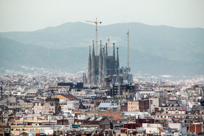 Sagrada familia and cityscape against mountains