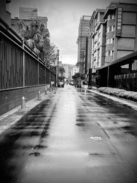 Empty road amidst buildings in city against sky