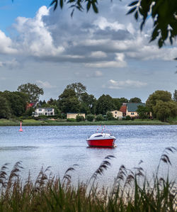 Sailboat in river by building against sky