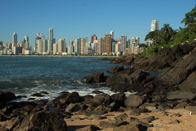 Calm sea with buildings against clear blue sky