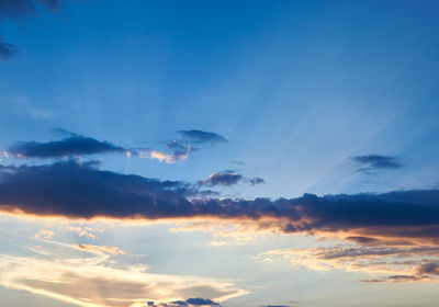 Low angle view of sunlight streaming through clouds