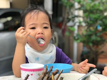 Close-up of girl having food at table in yard