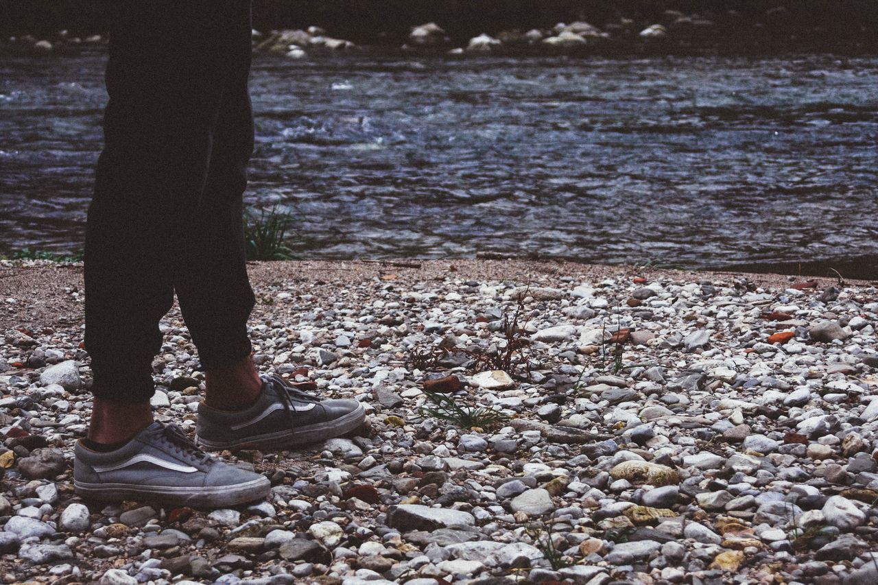 LOW SECTION OF MAN STANDING ON SHORE